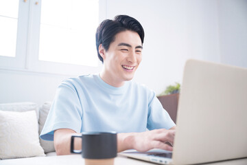 Smiling young man using a computer in a bright room Refreshing image of freelancers, engineers, designers, and other professionals