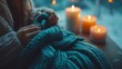 © IMAGINIAC - Woman's Hands Holding a Teal Knitted Blanket with Candles in the Background