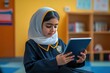 © Ali - Young Girl in Hijab Using a Tablet in a Classroom