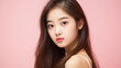 © ALA - Portrait of smiling asian teenager girl pink background.