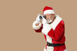 © Pixel-Shot - Santa Claus in glasses with camera taking photo on brown background
