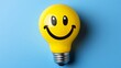 © Trusha - Yellow light bulb with a smiley face on it. The light bulb is sitting on a blue background