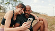 © Andrii Nekrasov - Close-up of athletic couple in love relaxing and using smartphone, front view