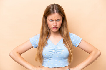 Wall Mural - Young caucasian woman isolated on beige background angry