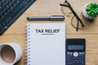 © arif_johari - Tax Relief text in notepad with office accessories.