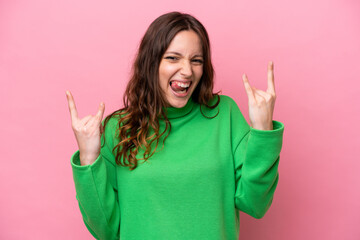 Wall Mural - Young caucasian woman isolated on pink background making horn gesture