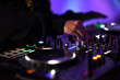 © chakorn - A DJ adjust audio mixing knobs on a vibrant console to creating an electric fun sound atmosphere. living the pulsating rhythm of nightlife.