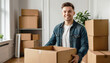 © Елена Пантюхина - Young happy Caucasian man holding big cardboard box standing in living room. Concept of moving to new house, apartment, office.