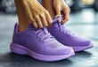 © RABBI - Woman Tying Purple Running Shoes in Gym