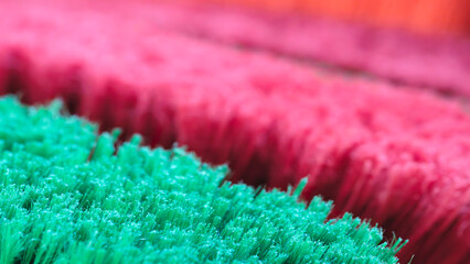 Poster - A close up of a green and red brush with a pink stripe. The brush is made of synthetic fibers and is used for cleaning