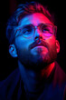© Gonzalo - Close-up portrait of a young man with glasses and a beard, illuminated by vibrant pink and blue neon lighting, evoking a thoughtful, modern aesthetic.