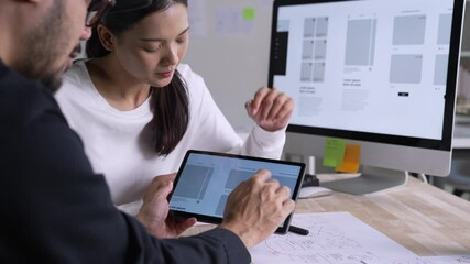 Wall Mural - ux ui designer testing prototype on a tablet, discussing and brainstorming on wireframes for a websi