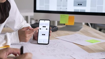 Wall Mural - ux ui designer testing prototype on a phone, discussing and brainstorming on wireframes for a websit