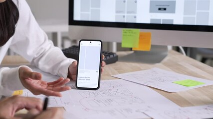 Wall Mural - ux ui designer testing prototype on a phone, discussing and brainstorming on wireframes for a websit