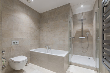 Wall Mural - Modern bathroom in beige tones with a glass shower, white bathtub and toilet.