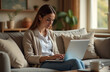 © OksKutsenko - Woman working on laptop at home in cozy living room setting