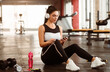 © Prostock-studio - Sports concept. Young lady with headphones listening to music from smartphone in gym