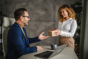 Wall Mural - Female colleague give present to her male colleague in the office