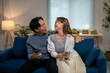 © Wasana - A man and a woman are sitting on a blue couch, holding cell phones and laughing