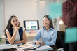 © Wasana - Two women are sitting at a desk with a computer monitor in front of them