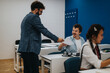 © qunica.com - A teacher hands an assignment to a smiling student in a modern classroom. Other students are focused on their work, highlighting a positive educational environment.