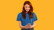 © Prostock-studio - Teen Girl Using Smartphone Playing Mobile Game Standing On Yellow Studio Background. Panorama