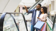 © Prostock-studio - Portrait Of Happy African American Couple At Escalator In Department Store, Young Black Spouses Shopping Together In Mall, Enjoying Making Purchases, Carrying Lots Of Bright Shopper Bags, Free Space