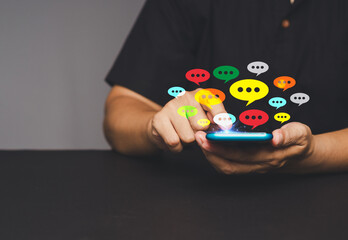 Wall Mural - close-up of hands using a smartphone with colorful chat bubbles.