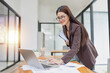 © SOMKID - Asian businesswoman working on laptop with finances analysis report at desk in office, business financing, accounting banking,