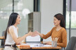 © SOMKID - Asian businesswoman making handshake with partner in meeting room, Greeting and corporate business handshake, 