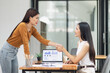 © SOMKID - Two people working together in office, Asian businesswoman making handshake with partner in meeting room, Greeting and corporate business handshake, 