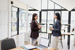 © SOMKID - Two Asian business female talking together with partner standing in office.