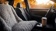 © Cozirlax - Cozy Car Interior with Soft Quilted Blanket, Warm Coffee Cup, and Beautiful Autumn Sunset Background Highlighting Comfort during Travel