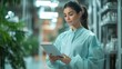 © somchai20162516 - Female doctor standing holding tablet full body on white background, wearing gown, attentive pose ready to check patient information