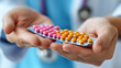 © sommersby - A healthcare worker displays a blister pack containing pink and orange pills while discussing treatment options with a patient