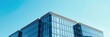 © Walapon - Modern office building with sleek glass facade against a clear blue sky, corporate, sunlight