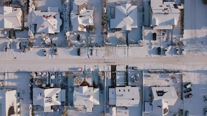 Wall Mural - Aerial view of residential neighborhood with houses and road streets covered in snow. European small town at winter season