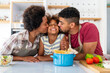 © NDABCREATIVITY - Happy african american parents and child having fun preparing healthy food in kitchen