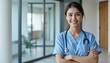 © Hathairat - Smiling healthcare professional in scrubs with stethoscope in a modern clinic.
