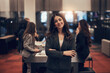 © Flamingo Images - Young businesswoman smiling in an office lobby with colleagues in the background