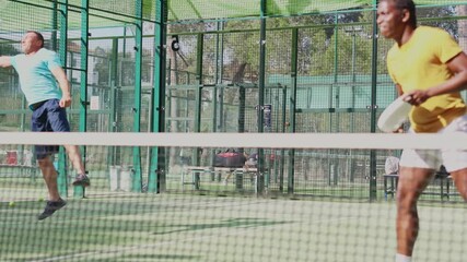 Wall Mural - African-american man in t-shirt playing padel tennis on court. Racket sport training outdoors. 