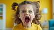 © Nataliia_Trushchenko - Young girl with her mouth wide open and her eyes wide open, looking angry. She is wearing a yellow shirt