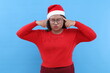 © ArvStd - Displeased young woman in red turtleneck,touching head with fingers isolated on blue background, studio portrait. Happy New Year celebration merry holiday concept