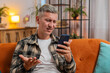 © Andrii Iemelianenko - Sad displeased Caucasian man using smartphone typing browsing, loses becoming surprised sudden lottery game results, bad news, fortune loss, fail, deadline, virus. Young guy with gray hair at home.