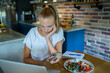 © Geber86 - Woman using laptop on kitchen table while eating healthy meal