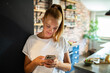 © Geber86 - Young woman holding smartphone in modern kitchen
