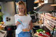 © Geber86 - Young woman filming cooking tutorial in kitchen with fresh vegetables and eggs