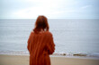 © Connect Images - Blurry woman in a cozy sweater gazing at the serene ocean from a sandy beach, Belgium