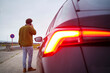 © Connect Images - Man standing by a car on the roadside talking on the phone under overcast sky, Belgium