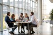 © NRdS - A softly blurred scene of business people gathered around a table in a modern office.